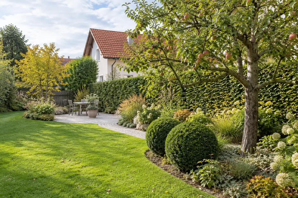Gepflegter Garten mit Hecken, Obstbaum und Terrasse – KI-generiertes Symbolbild